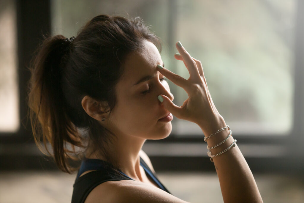 Young attractive woman in Alternate Nostril Breathing, studio ba